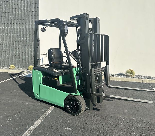 A green forklift is parked in a parking lot in front of a building