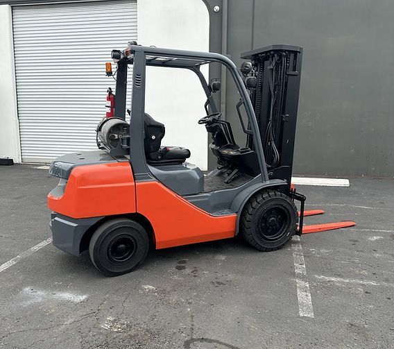 A forklift is parked in a parking lot in front of a building.