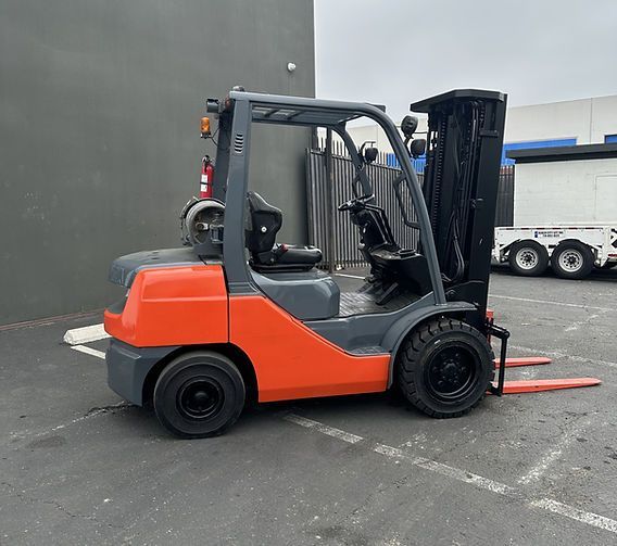 A forklift is parked in a parking lot in front of a building.