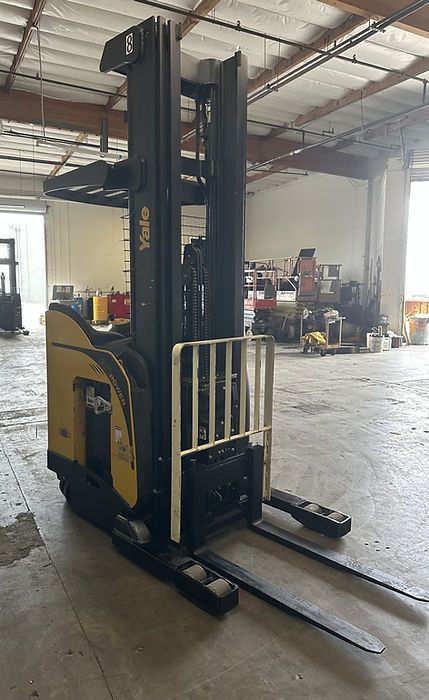 A yellow and black forklift is sitting in a warehouse.