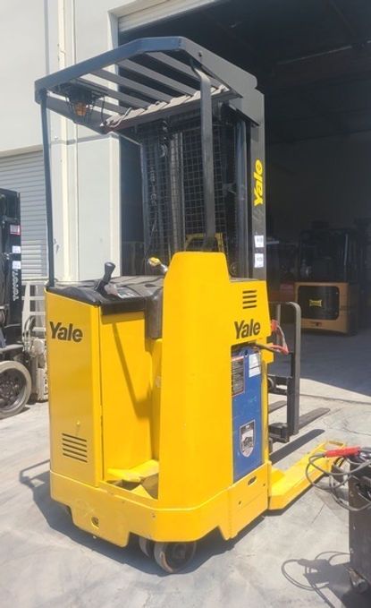 A yellow yale forklift is parked in front of a building