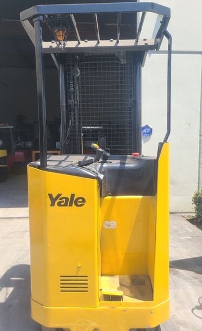 A yellow forklift is parked in front of a building.
