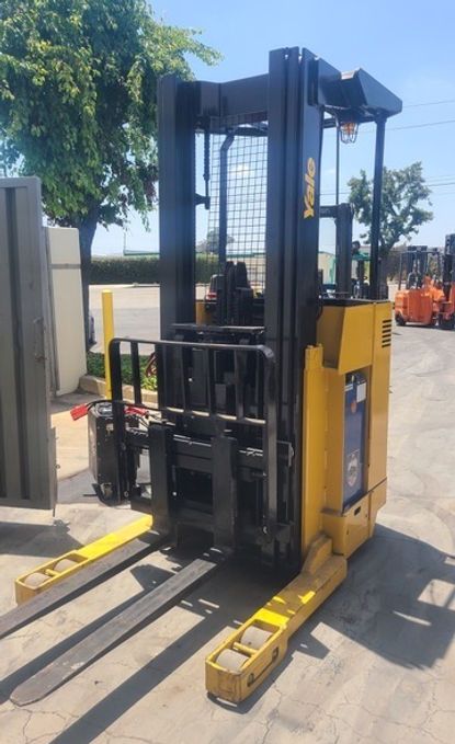 A yellow and black forklift is parked in a parking lot.