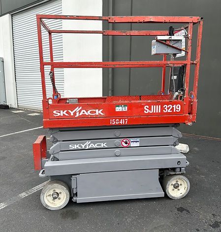 A red skyjack scissor lift is parked in a parking lot.