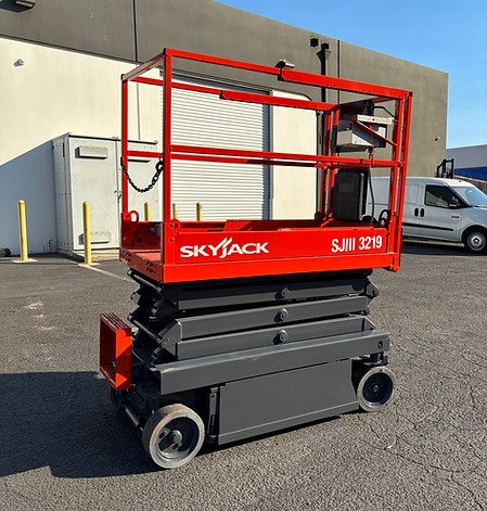 A red skyjack scissor lift is parked in a parking lot