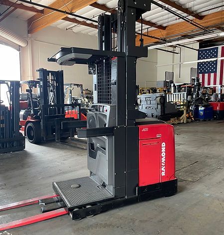 A raymond forklift is parked in a warehouse next to other forklifts.