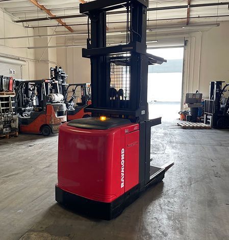 A red forklift is parked in a warehouse with other forklifts