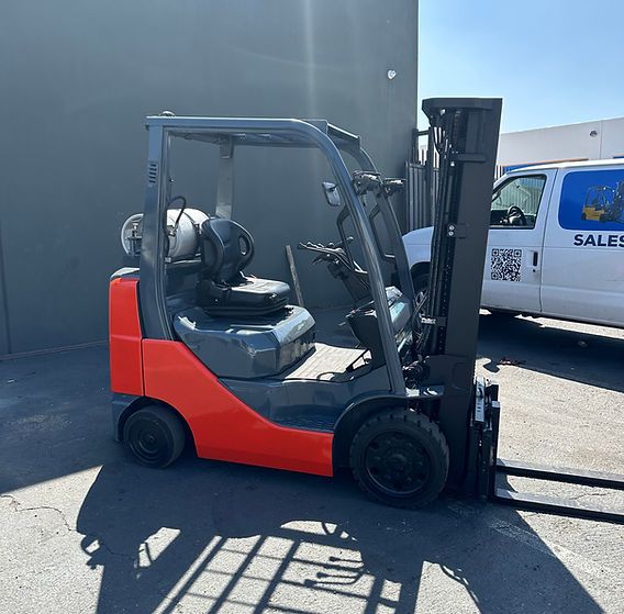 A forklift is parked next to a sales van