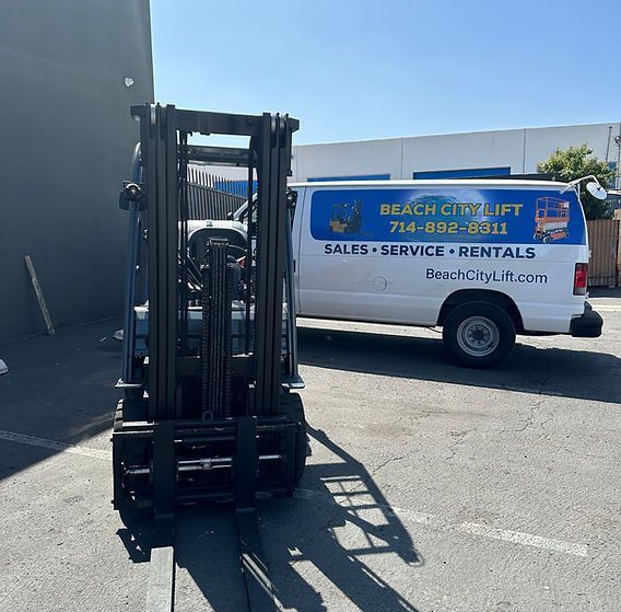 A forklift is parked in front of a beach city lift van