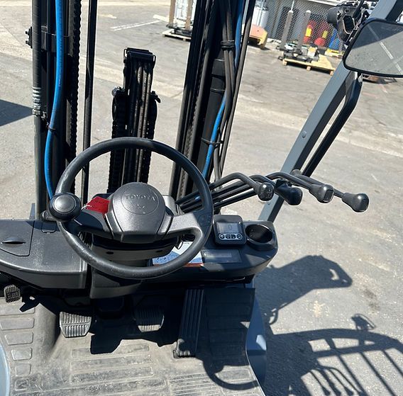 The inside of a forklift with a steering wheel and controls
