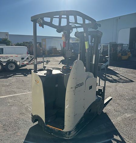 A forklift is parked in a parking lot in front of a building.