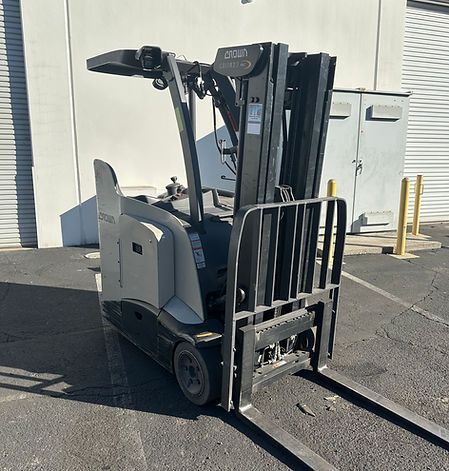 A forklift is parked in a parking lot in front of a building.