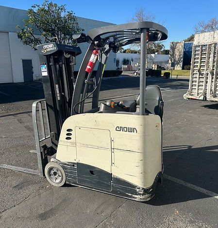 A forklift is parked in a parking lot in front of a building.