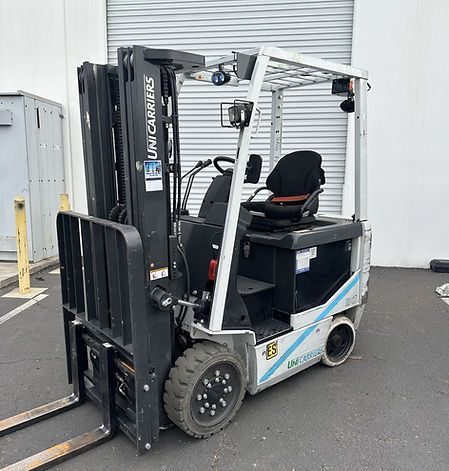 A forklift is parked in a parking lot in front of a building.
