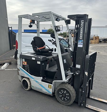 A forklift is parked in a parking lot in front of a building.