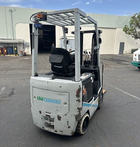 A forklift is parked in a parking lot in front of a building.
