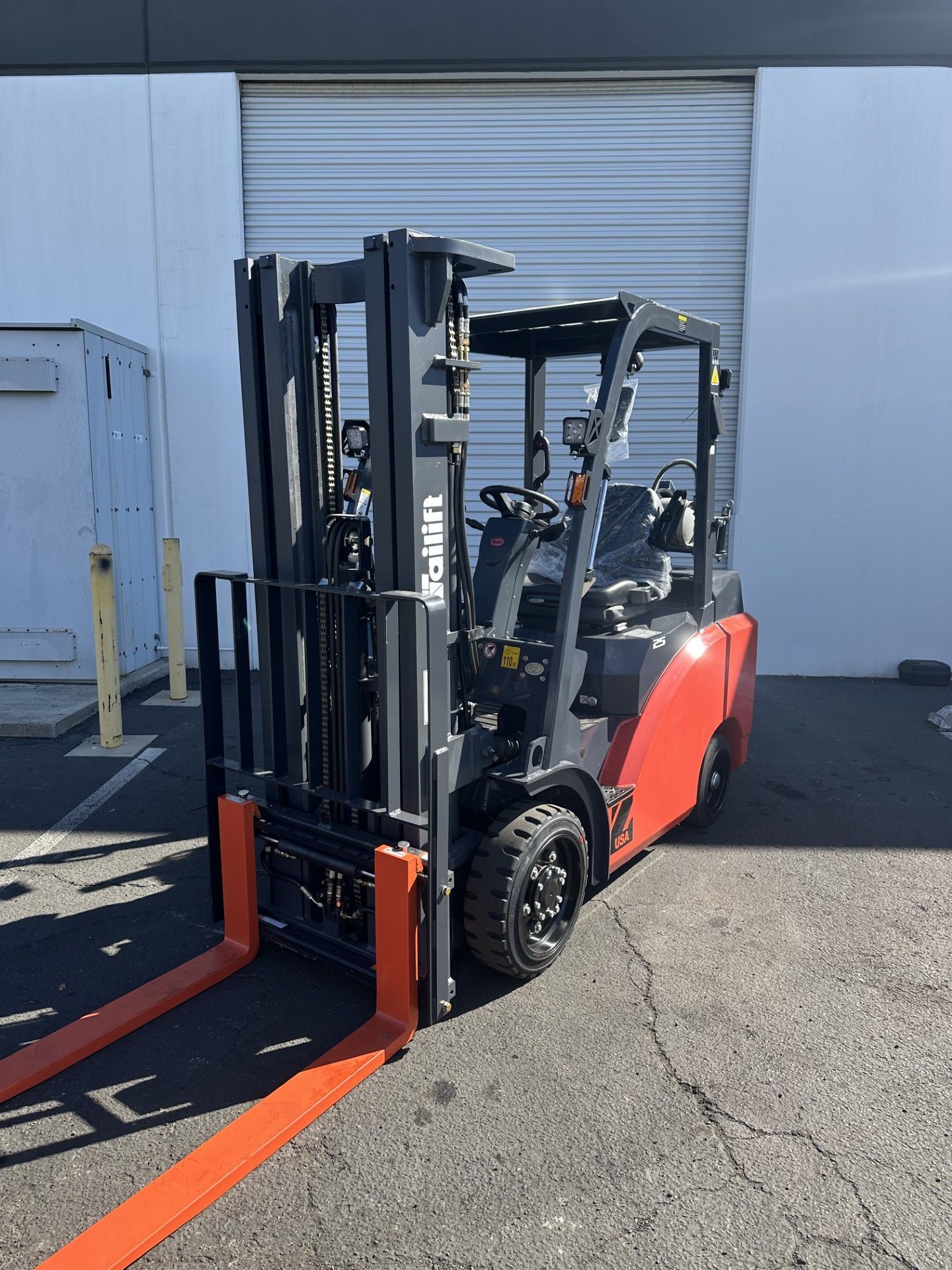 A red and black forklift is parked in front of a building.