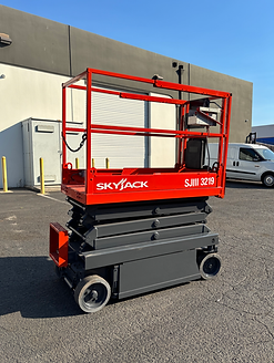 A skyjack scissor lift is parked in front of a building.