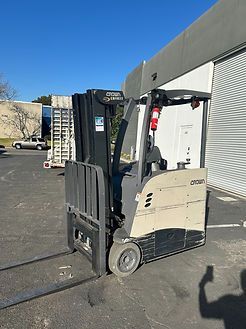 A forklift is parked in a parking lot in front of a building