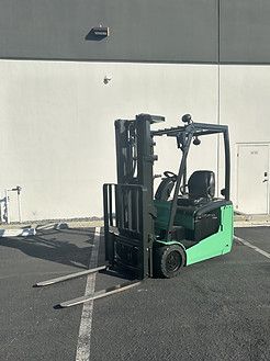 A green forklift is parked in a parking lot in front of a building