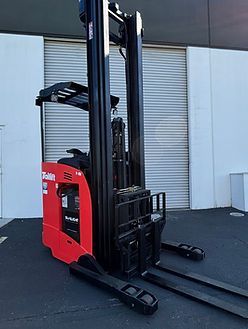 A red and black forklift is parked in front of a building.