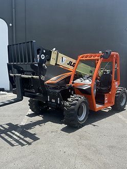 A forklift is parked in a parking lot in front of a building
