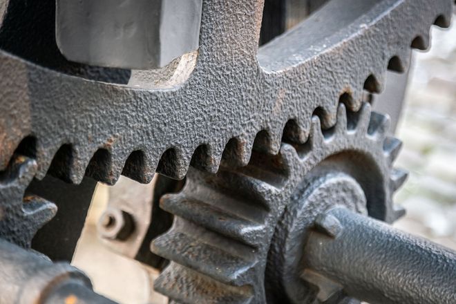 Close-up of three interlocking black metal gears, part of a machine.