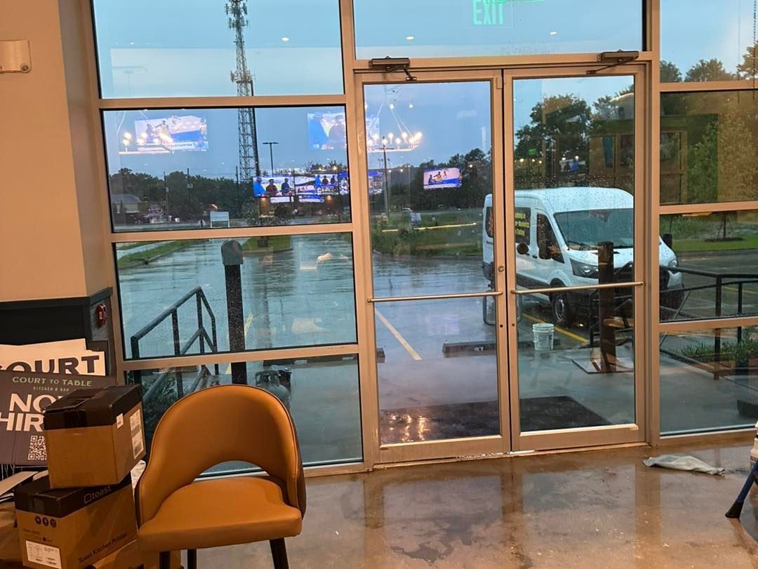 A view through large glass doors showing a rain-slicked parking lot with a white van at dusk.