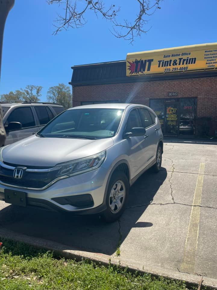 A silver Honda CR-V parked in front of a brick business building with a yellow sign reading 