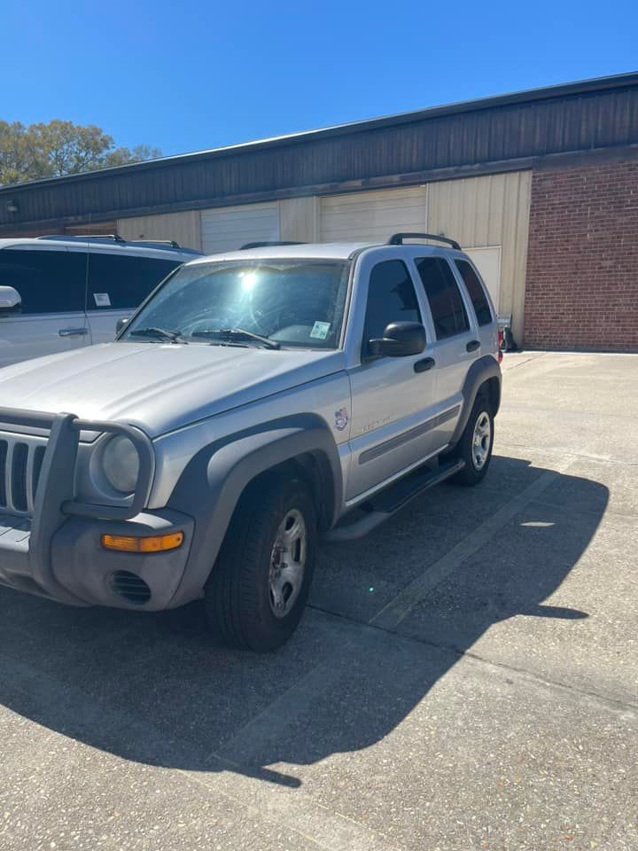 A silver Jeep Liberty SUV parked in an outdoor lot on a sunny day.
