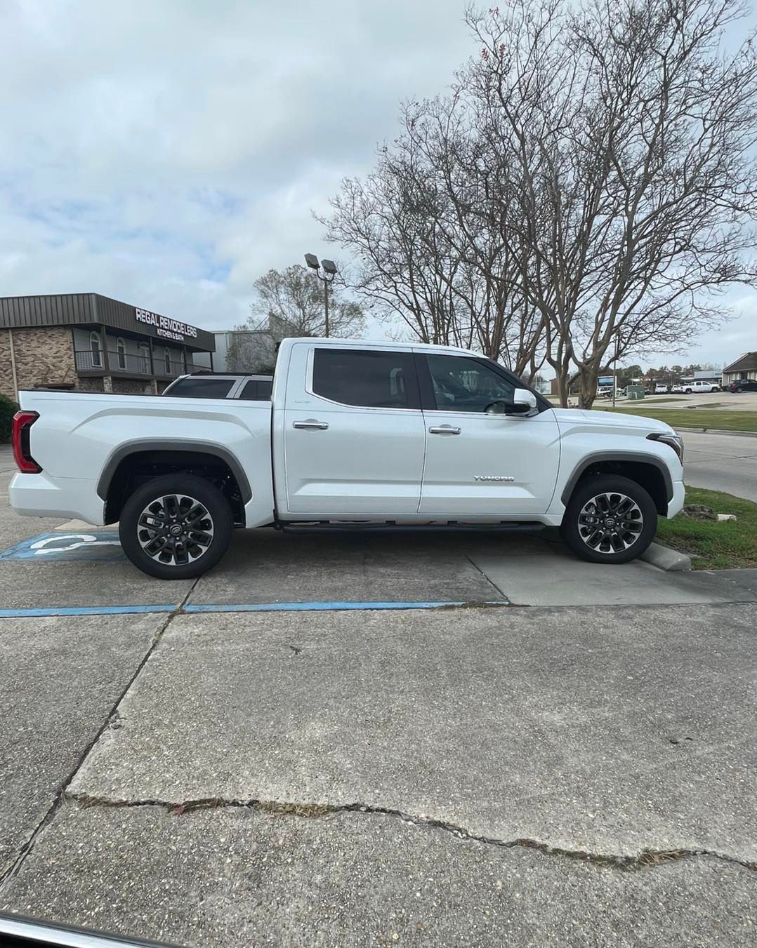 A white pickup truck parked in an outdoor lot on a cloudy day.