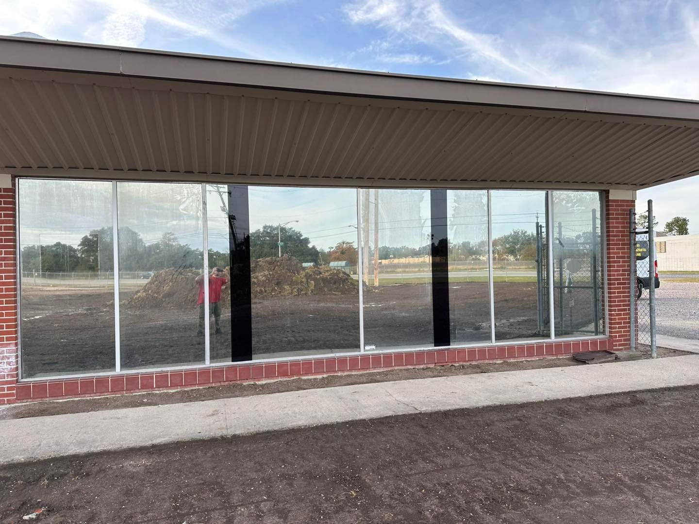 A long, ground-level brick building with wide, reflective glass windows under a large, overhanging roof.
