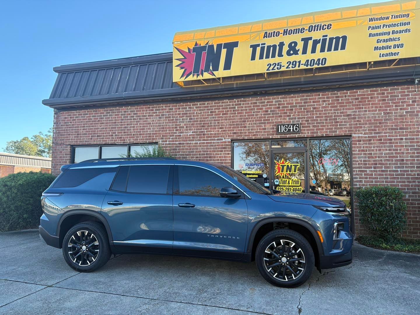 A blue SUV parked in front of a brick business building with a sign that reads 