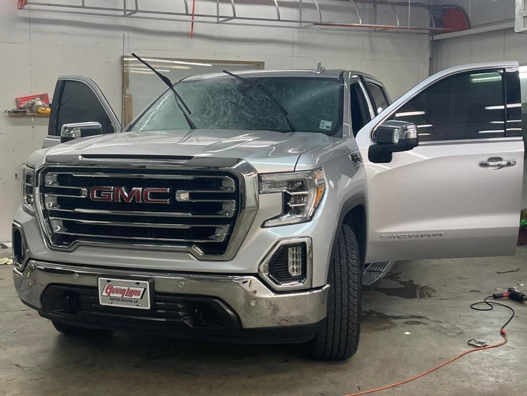 A silver GMC Sierra pickup truck with its doors open parked inside a garage.