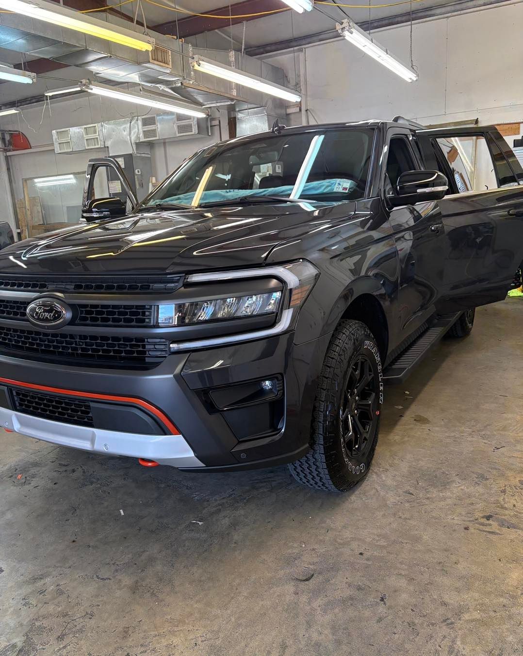 A dark grey Ford Expedition Timberline parked in a well-lit workshop with its front passenger door open.