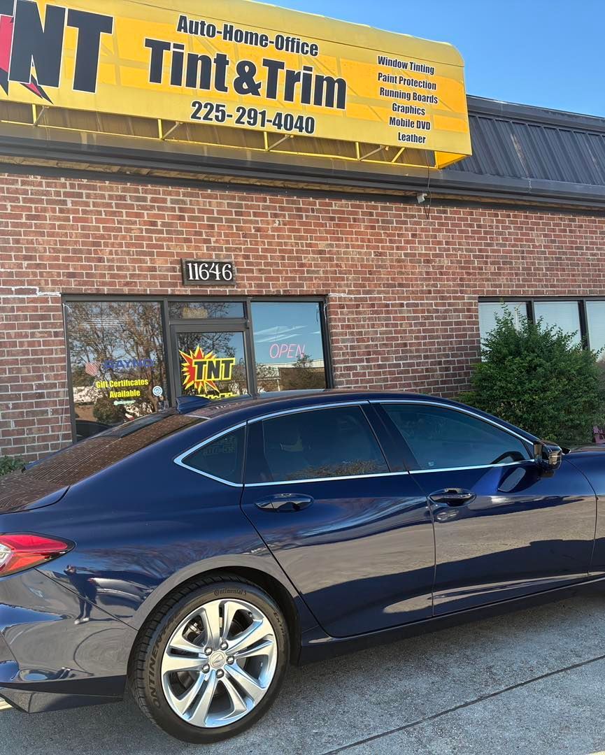 A dark blue sedan parked in front of a brick building with a yellow 