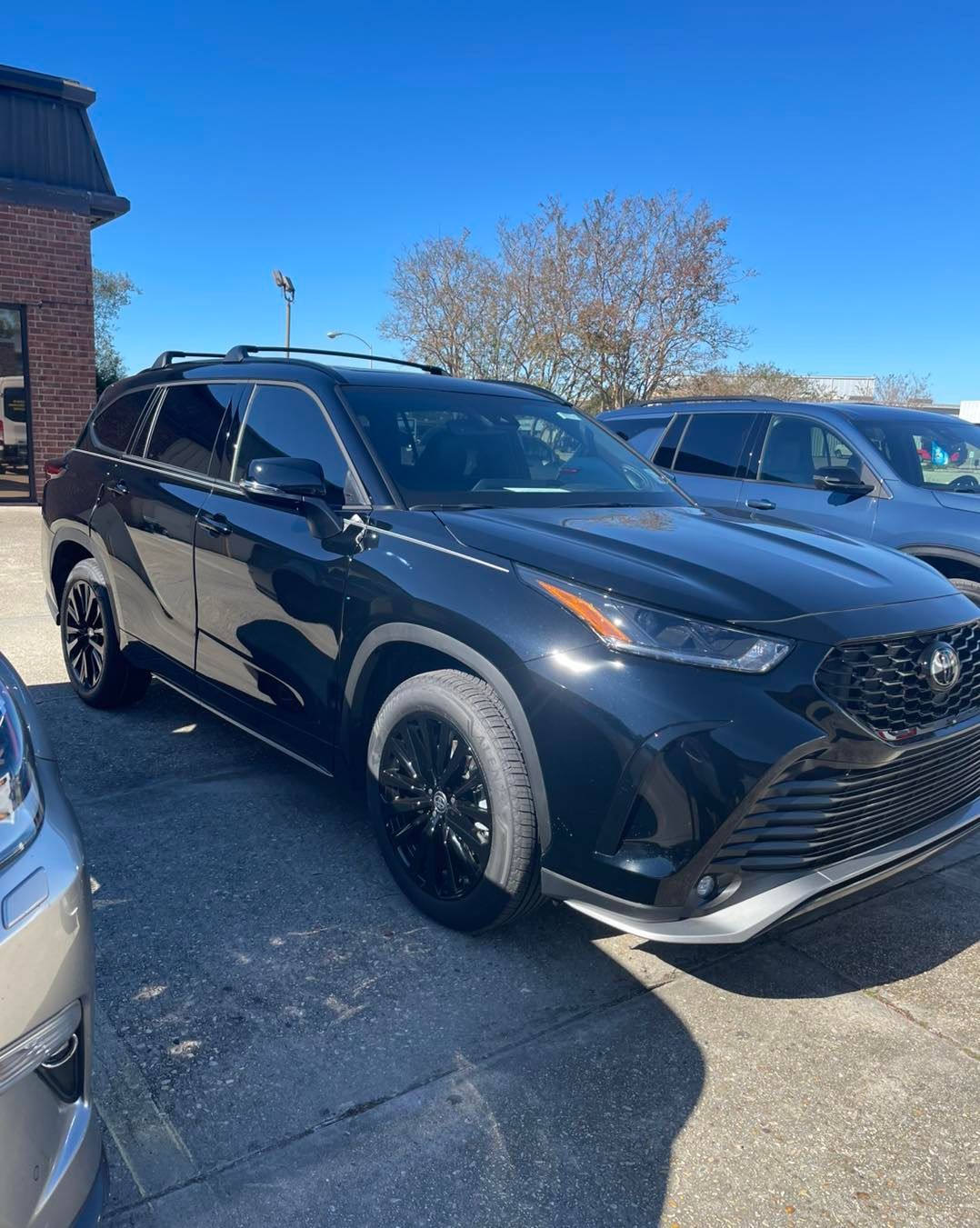 A black Toyota Highlander SUV parked in an outdoor lot on a sunny day.