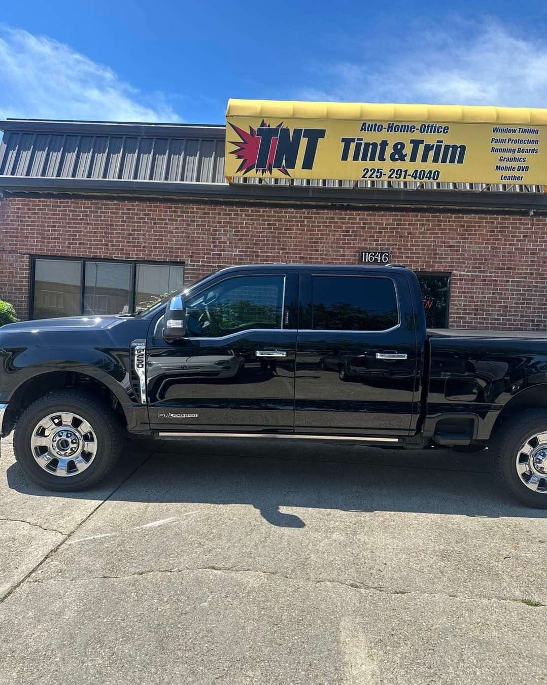 A black pickup truck parked in front of a brick building with a yellow sign that reads 