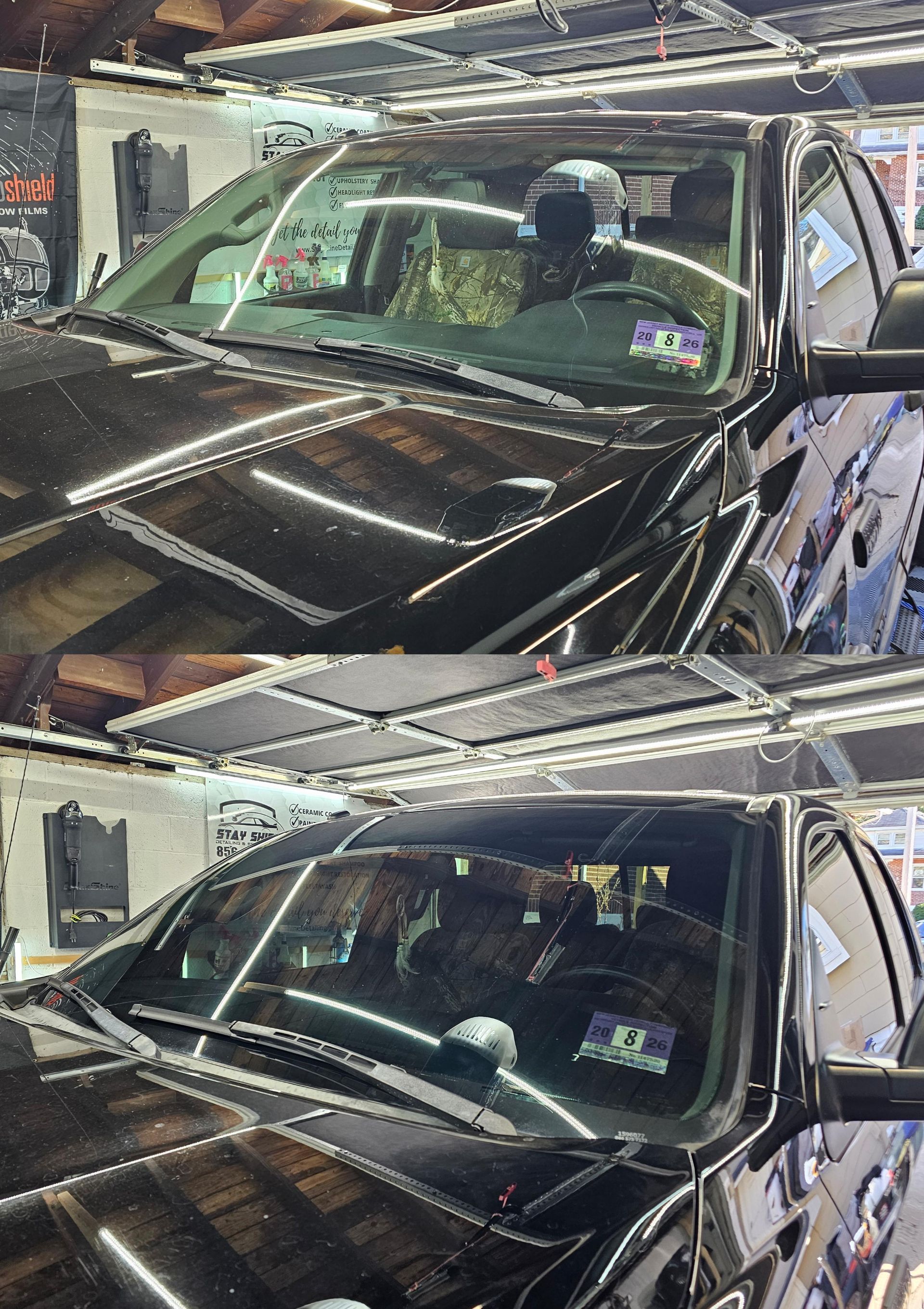 Black truck, front view, inside a shop with a device mounted on the windshield, possibly for repairs.