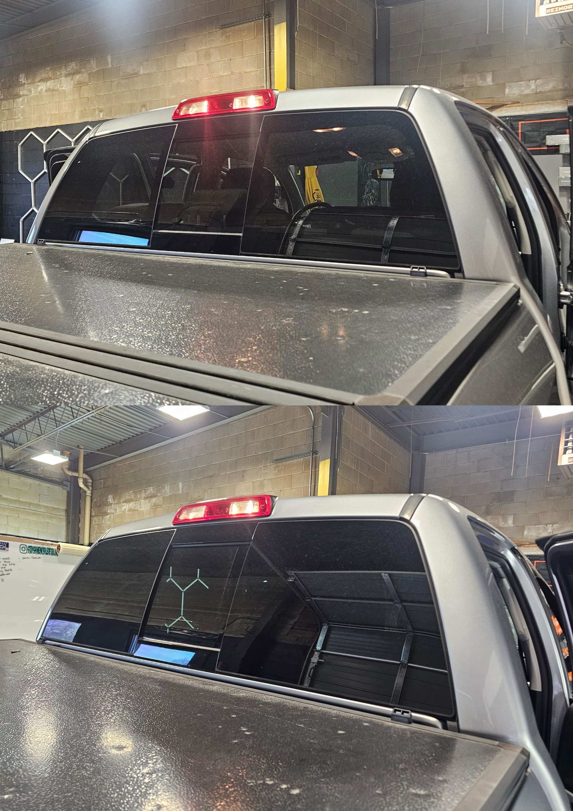 Rear view of a silver pickup truck with tinted windows, showing the back of the cab under a red brake light.