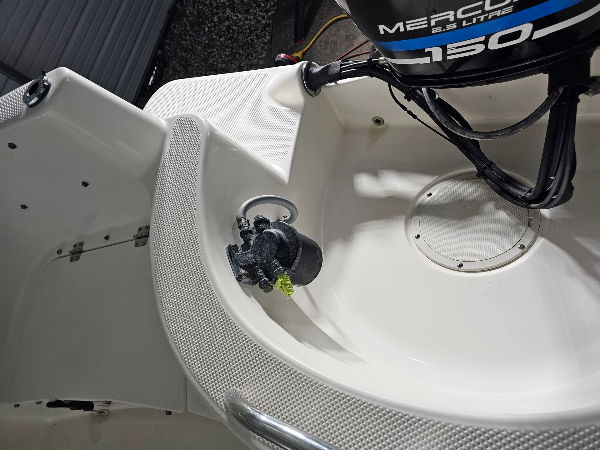 White boat interior with a Mercury outboard motor and a circular, black object mounted on the side.