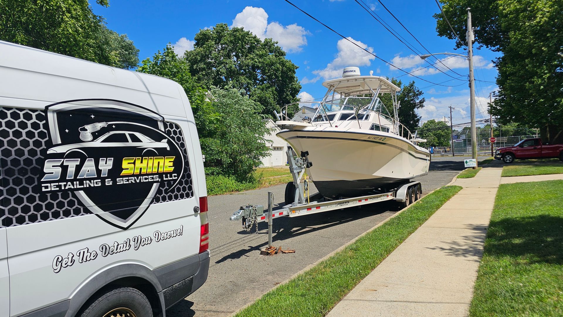 White boat on a trailer parked next to a white van with 