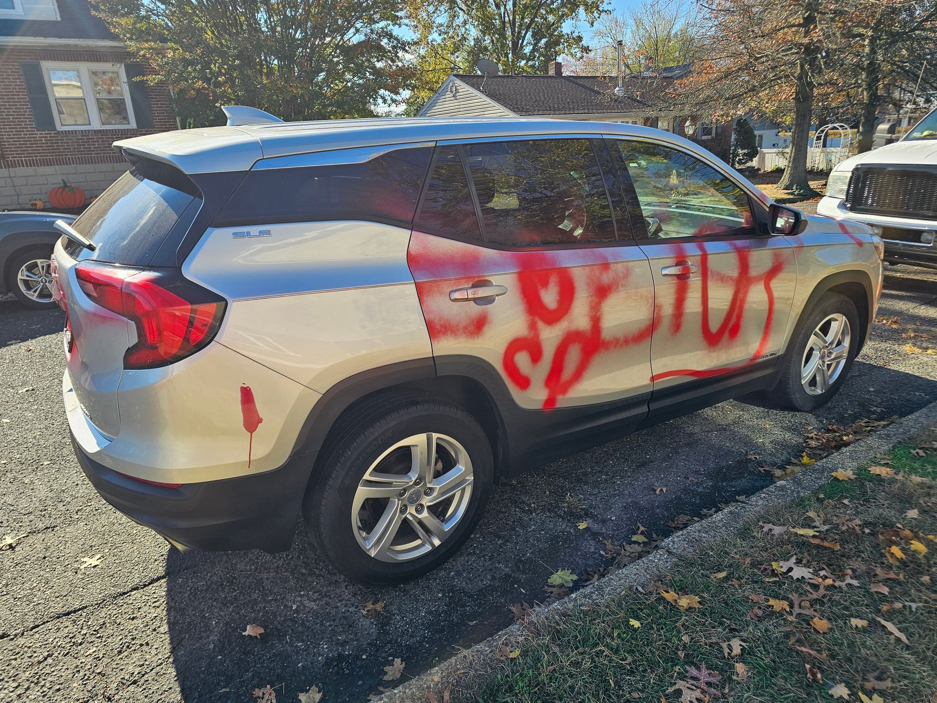 Silver SUV with red graffiti on the side, parked on a driveway.