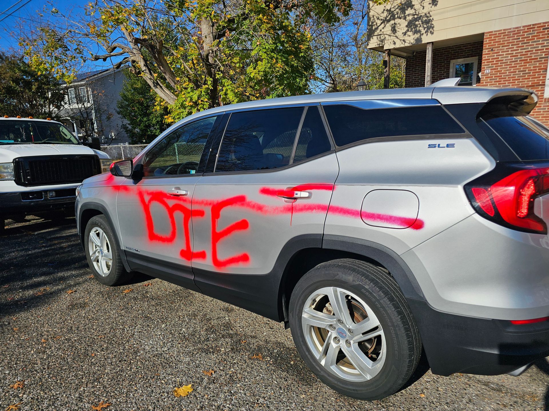 Silver SUV vandalized with red spray-painted word 