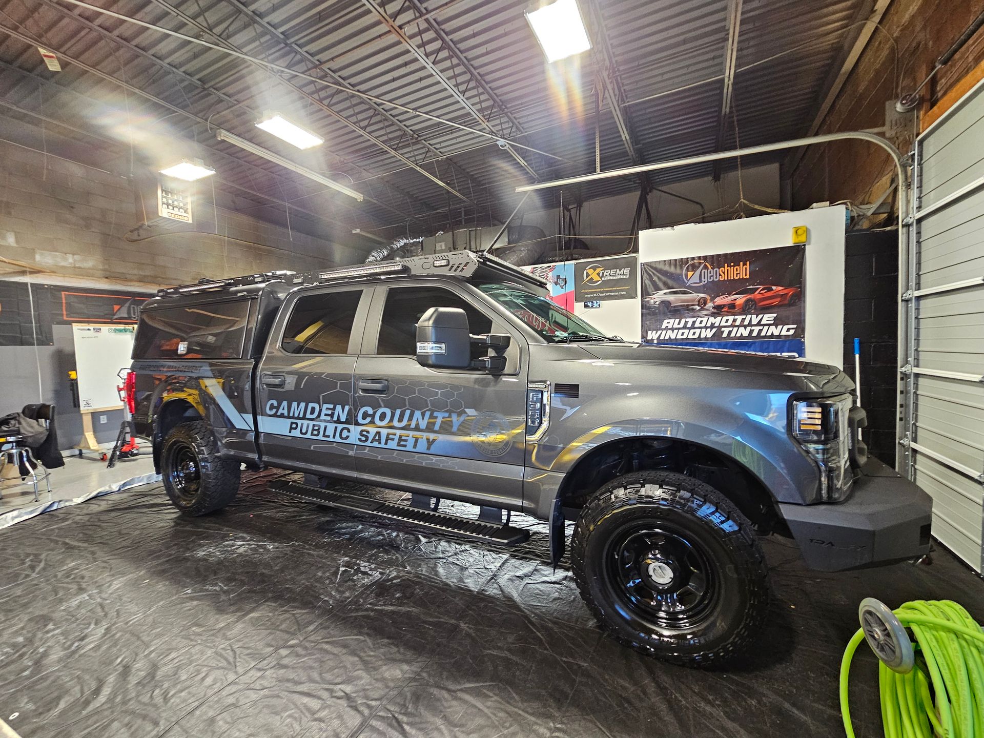 Gray Camden County Sheriff pickup truck inside a garage being washed with a hose.