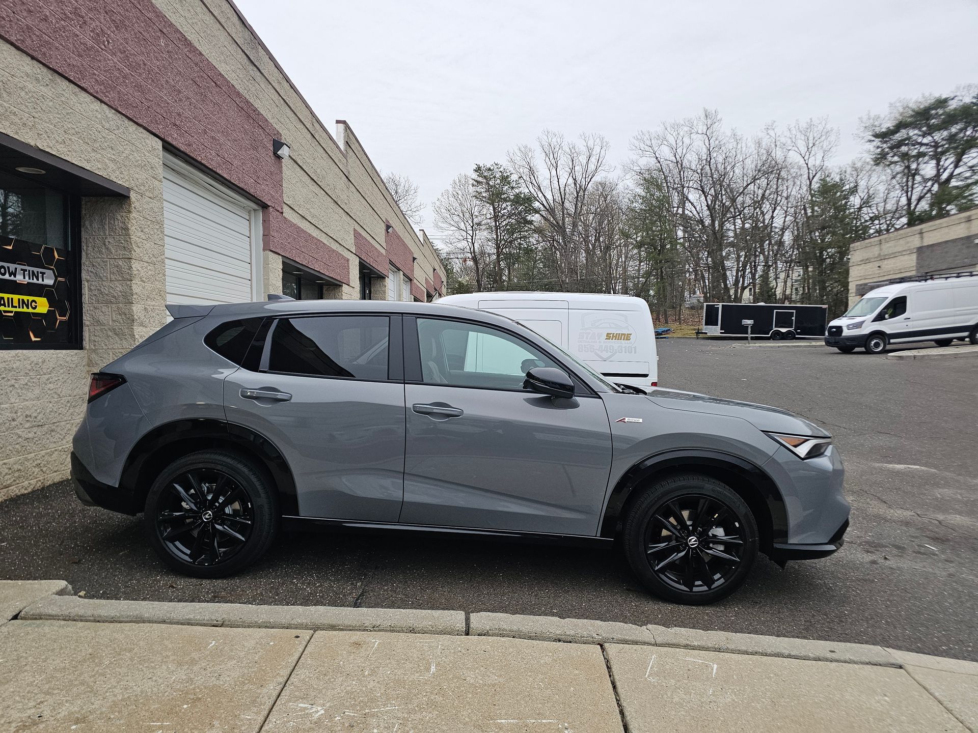 Gray Acura SUV parked outside a building with white garage doors. Black wheels.