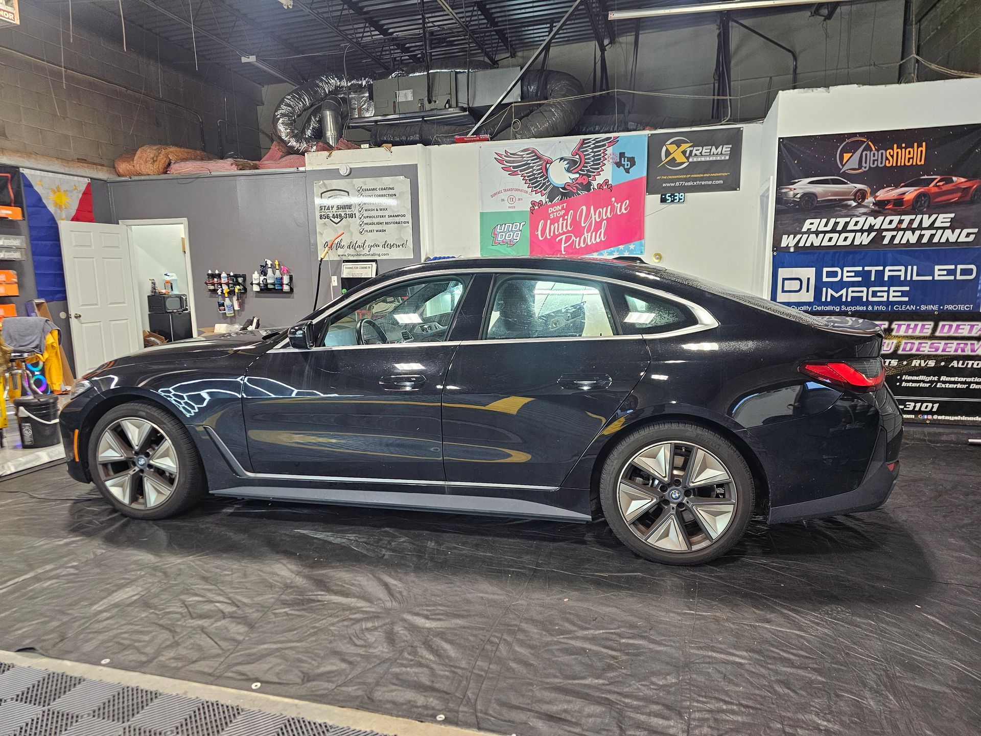 Black car in an automotive window tinting shop.