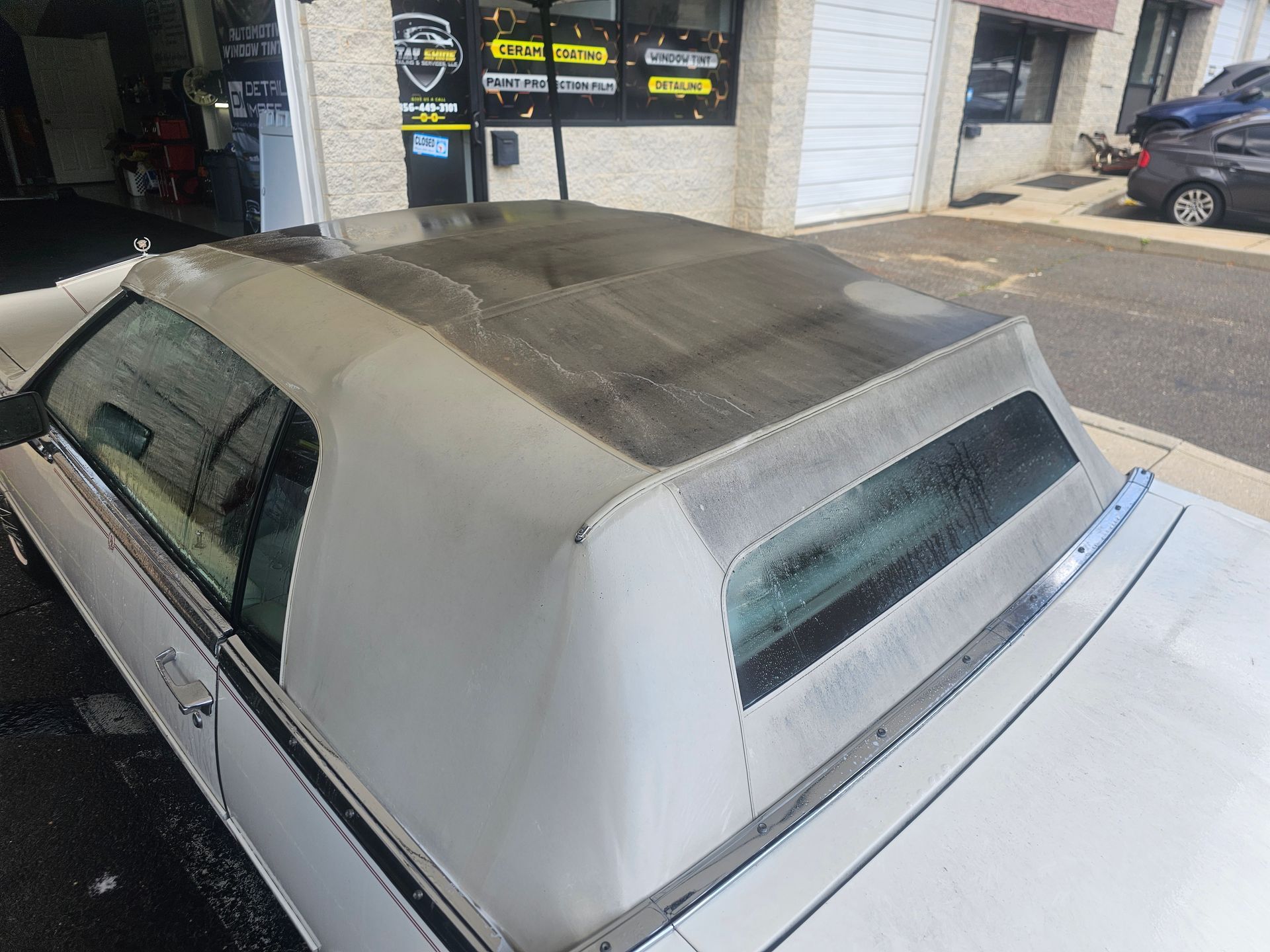 White car's roof and window being cleaned outside a business.