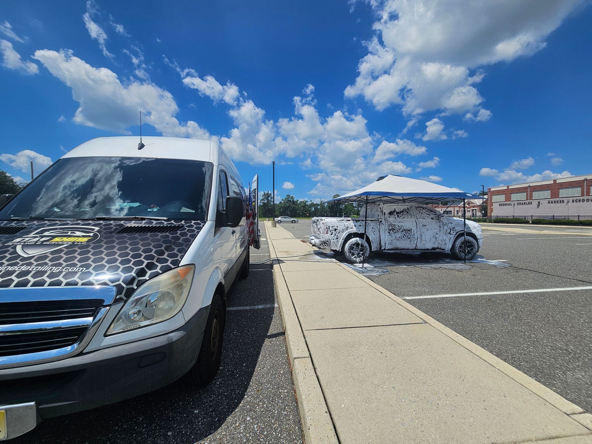 Van and golf cart covered in foam soap, parked on a sunny day in an empty lot.