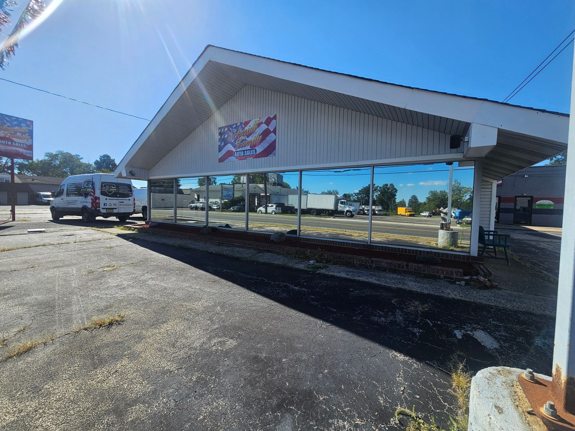 Exterior of a building with reflective windows and an American flag. A van is parked to the left.
